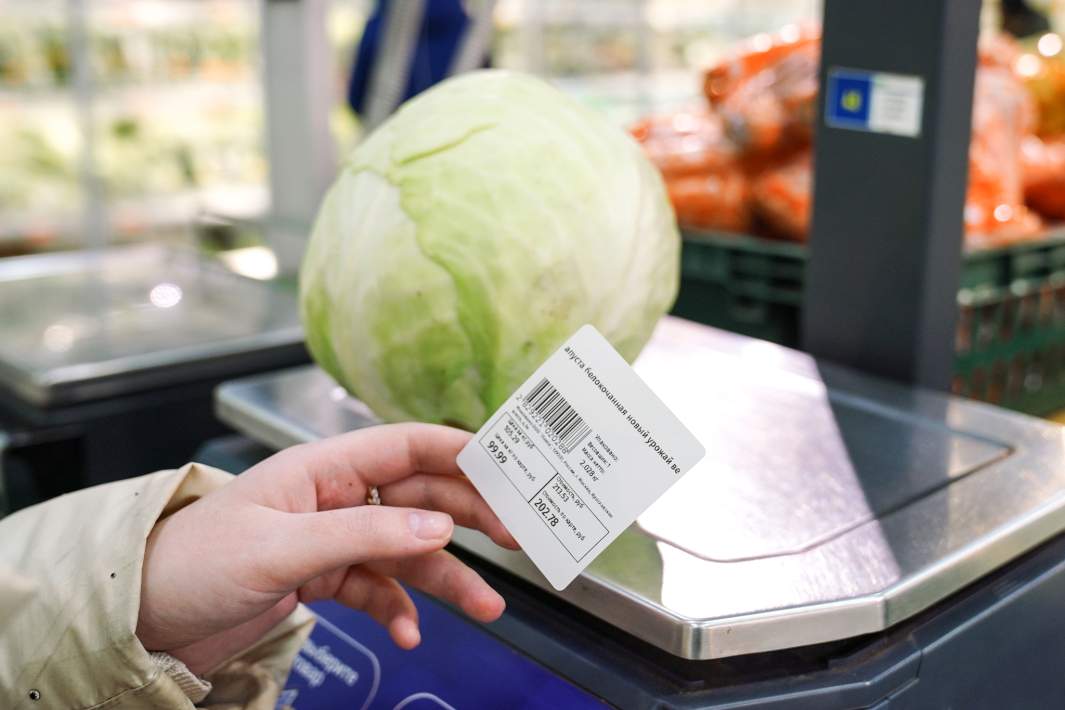Покупатель взвешивает капусту в магазине