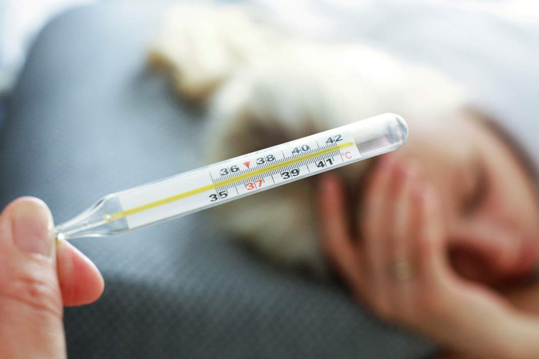 Женщина держит градусник в руке