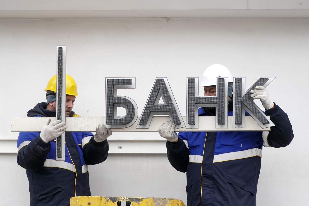 Рабочие демонтируют вывеску банка