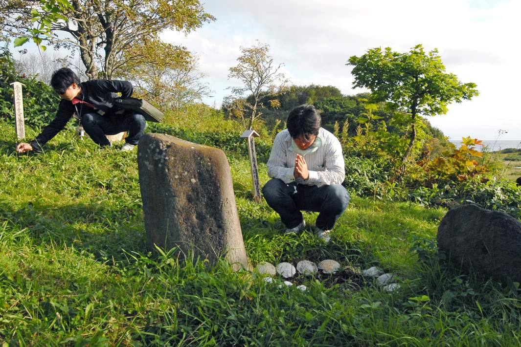 Представители японской безвизовой делегации на старом японском кладбище в Южно-Курильске на острове Кунашир
