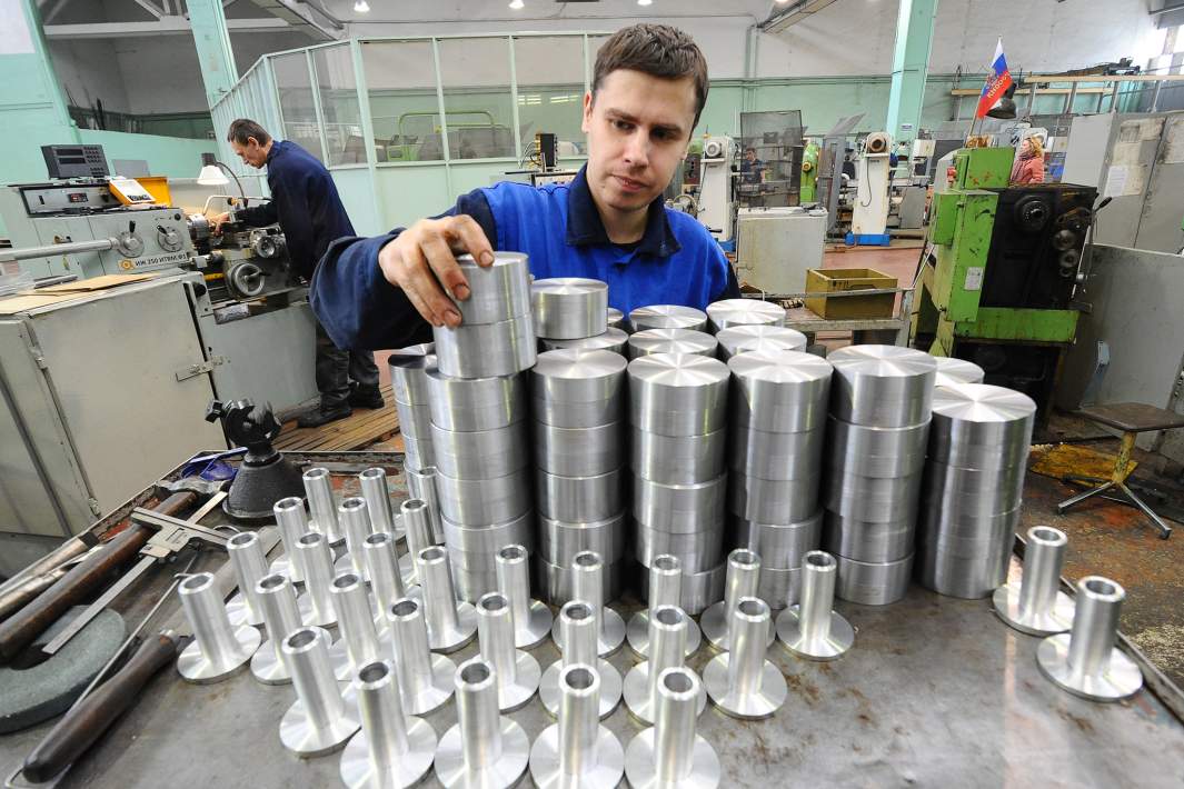 Токарь производит визуальный осмотр заготовок деталей будущих изделий в механообрабатывающем цехе