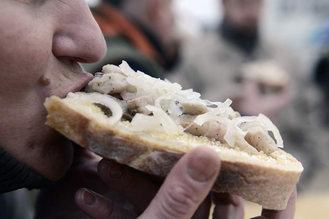 Мужчина ест селедку с луком 