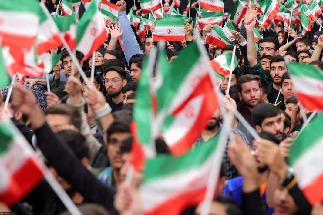 Иранские студенты держат флаги Ирана на митинге 