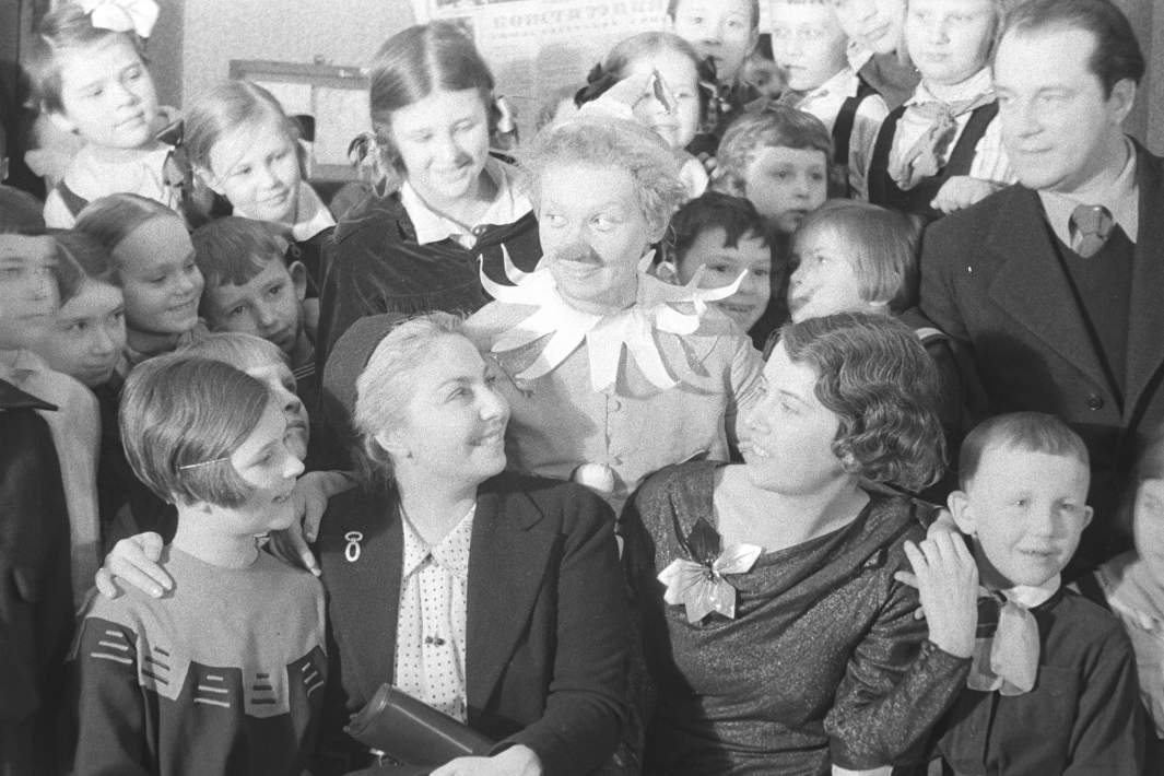 Актриса Клавдия Коренева в гриме «Буратино» (в центре), испанская писательница Мария Тереса Леон (вторая слева) и режиссер Наталья Сац (вторая справа) среди зрителей на юбилейном представлении «Золотого ключика» в честь первой годовщины работы Центрального детского театра в новом здании на площади Свердлова. 5 февраля 1937 года