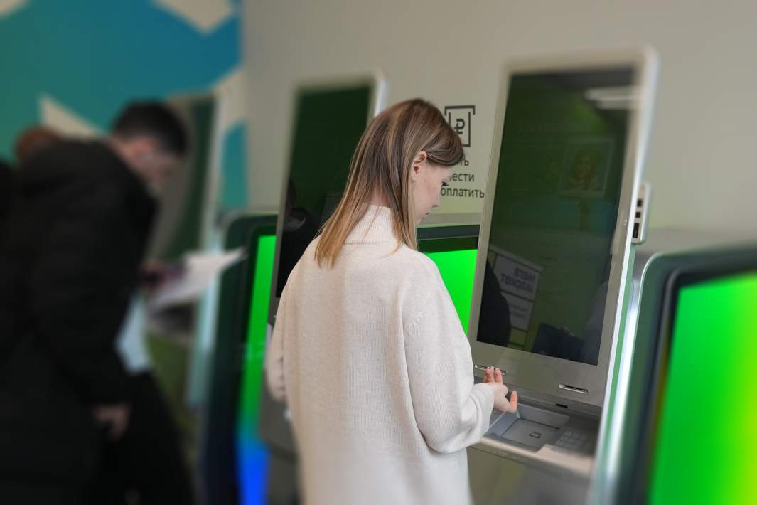 Девушка снимает деньги с банкомата 