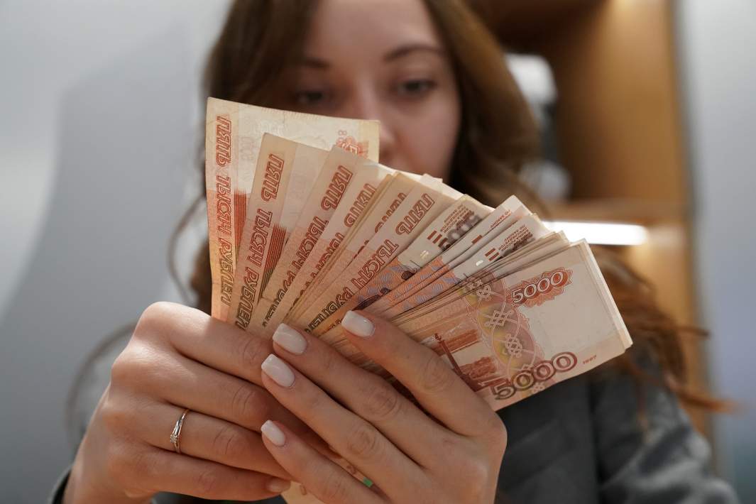 Девушка держит рублевые купюры 