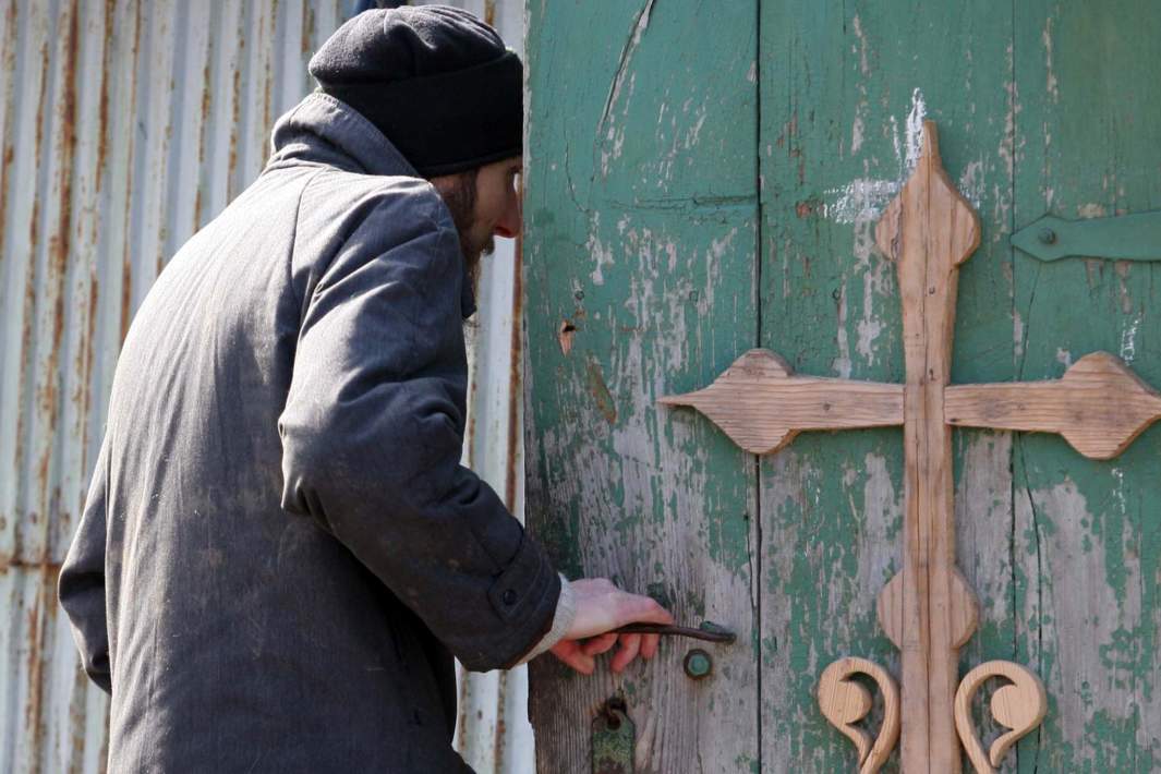 Мужчина входит в дверь с православным крестом