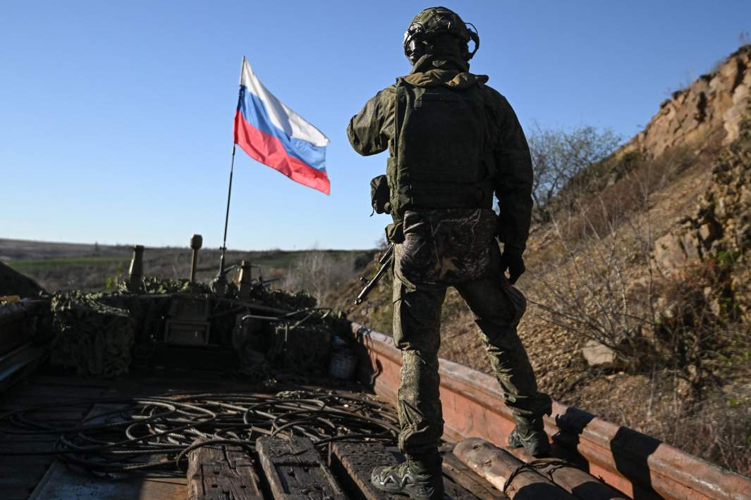 Военнослужащий ВС РФ на фоне флага в зоне СВО  