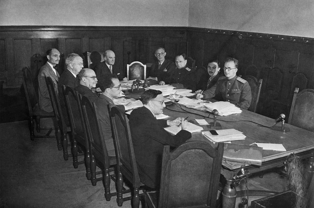Судьи Нюрнбергского процесса просматривают документы за столом в комнате для совещаний во Дворце правосудия