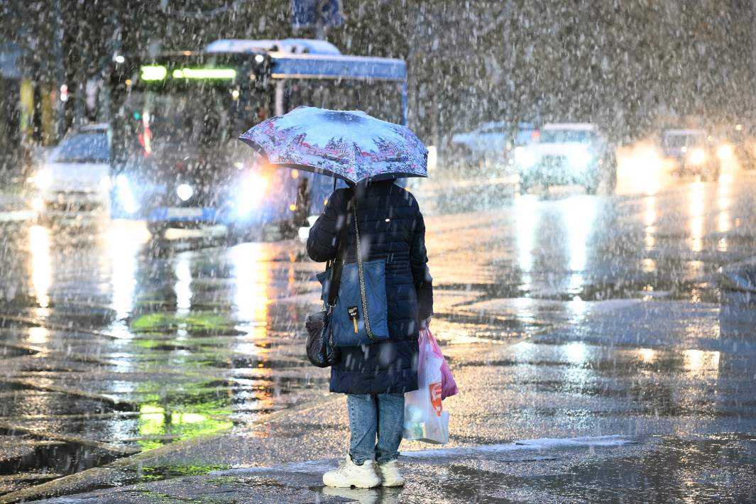 Женщина во время снегопада на одной из улиц Москвы