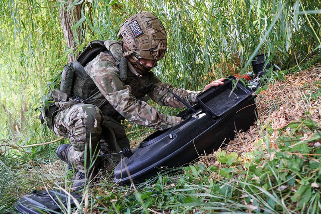 Военнослужащий с катером на дистанционном управлении для доставки грузов по воде