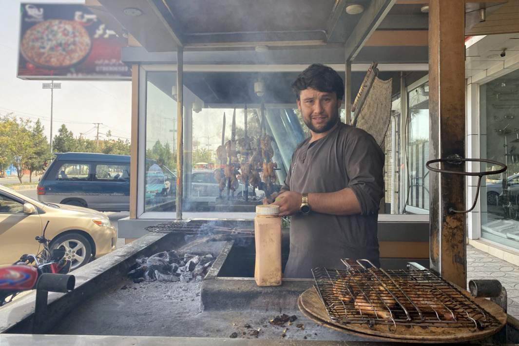 Мужчина жарит мясо на углях 