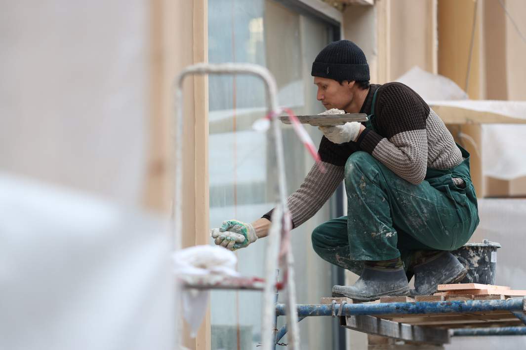 Рабочий штукатурит фасад 