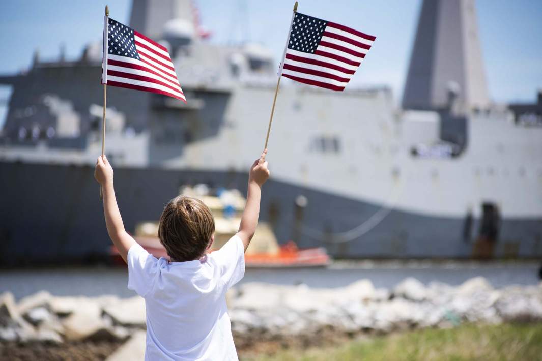 Мальчик с флагами США на фоне военного корабля