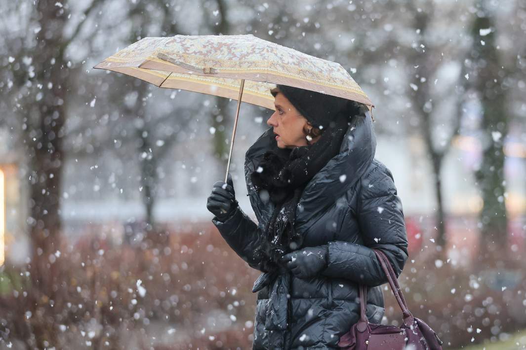 Женщина под зонтом во время снегопада 