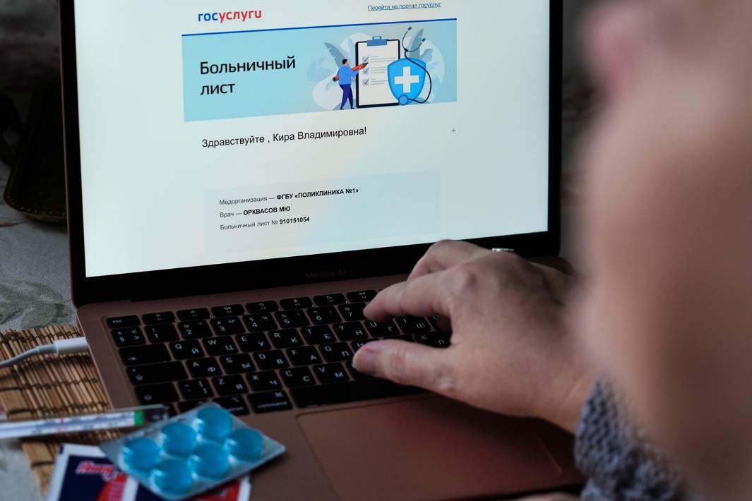 Женщина перед ноутбуком оформляет больничный лист