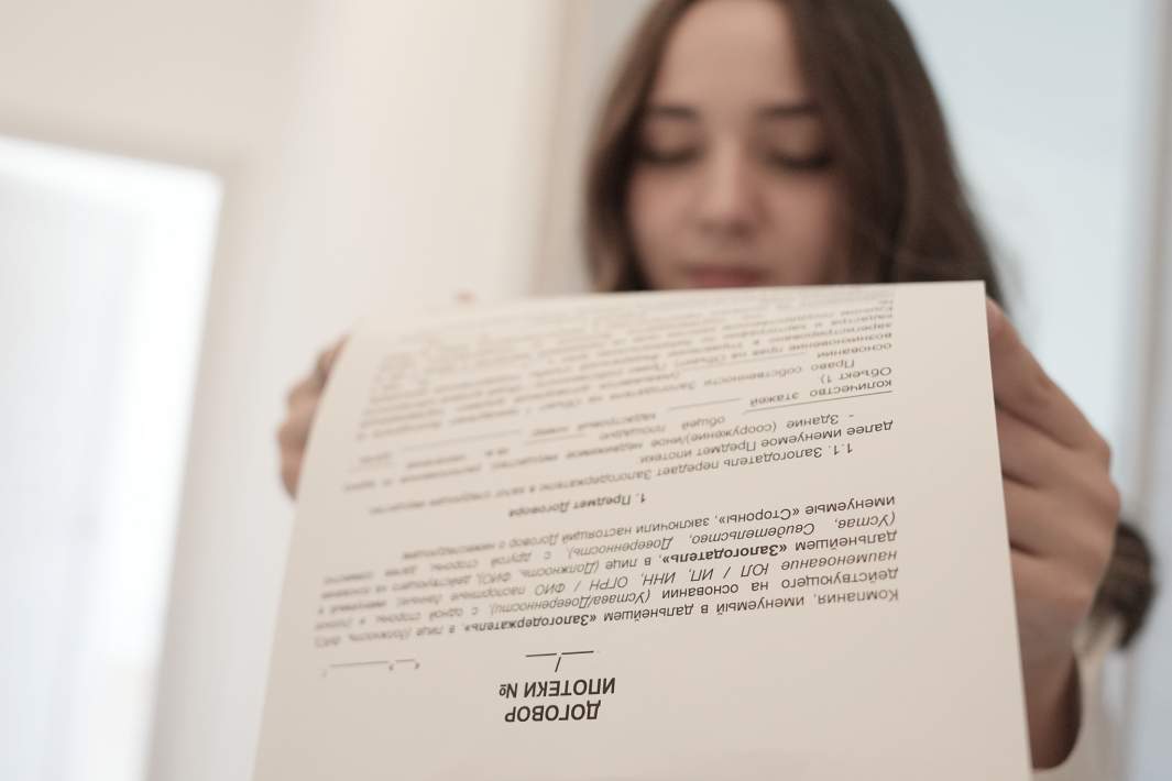 Девушка держит в руках договор ипотеки 