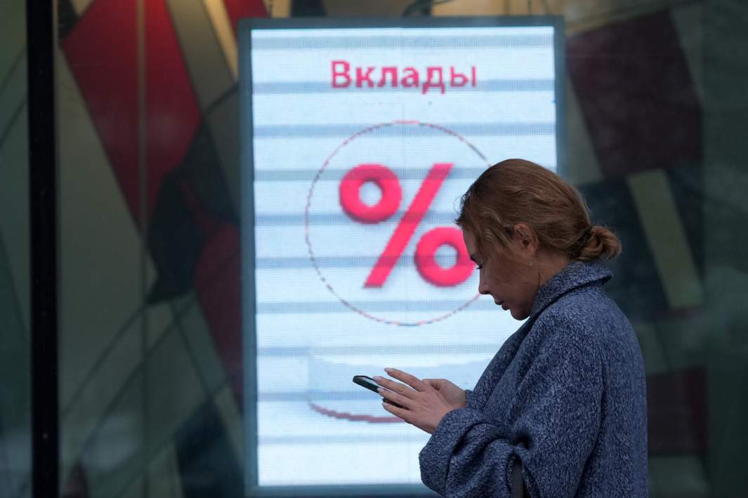 Девушка идет по улице мимо рекламы в витрине банка