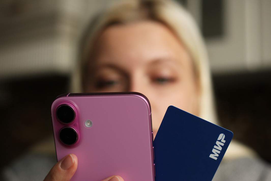 Девушка держит в руке телефон и банковскую карту 