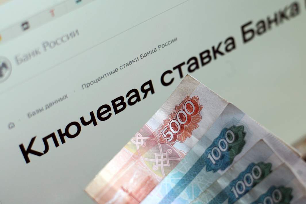 Купюры номиналом тысяча и пять тысяч рублей на фоне сообщения о ключевой ставке Банка России
