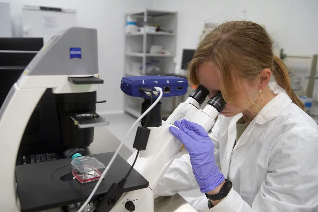 Девушка смотрит в микроскоп 