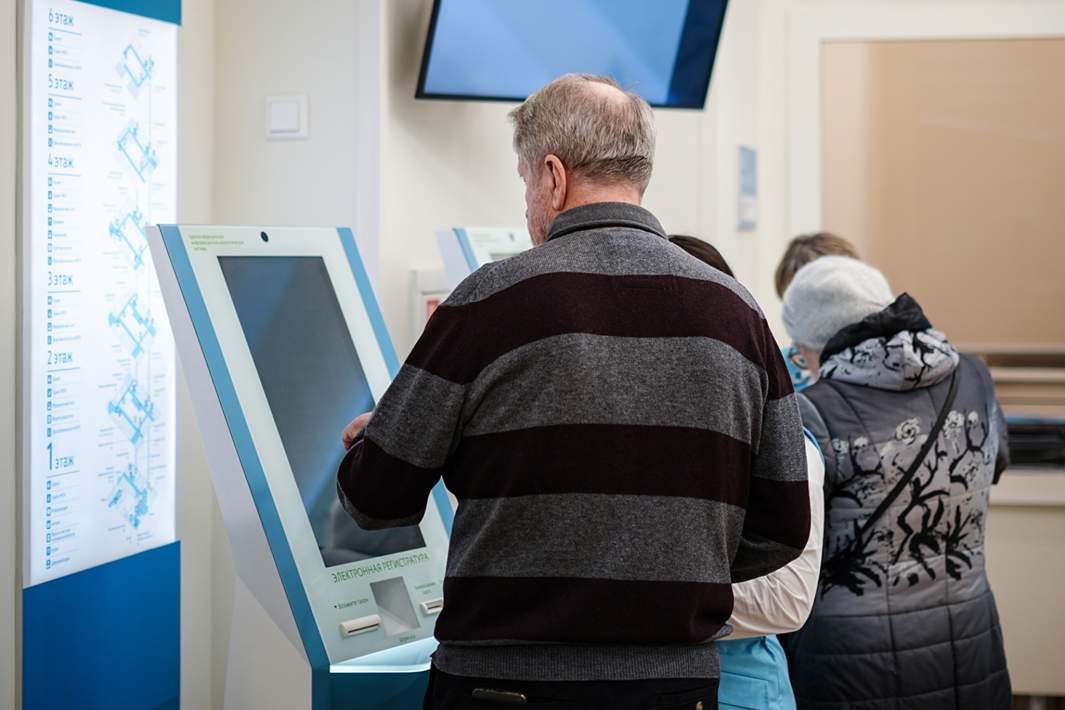 Пенсионер берет талон в поликлинике 