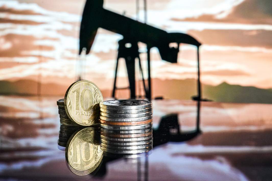 Монеты на фоне нефтяных вышек