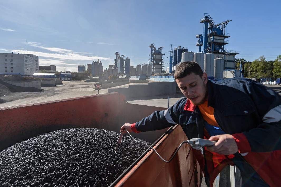 Рабочий измеряет температуру асфальтобетона