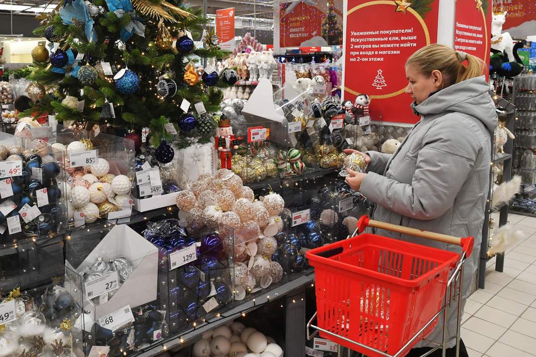 Покупательница выбирает ёлочные игрушки в гипермаркете