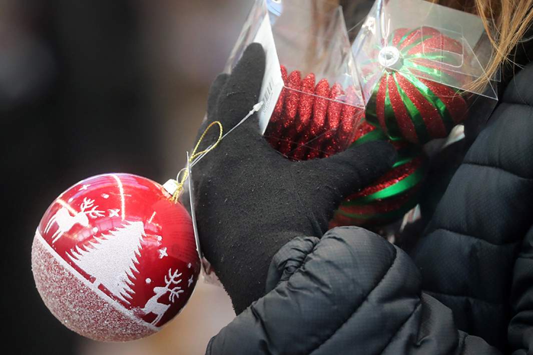 Посетительница держит елочные игрушки в магазине