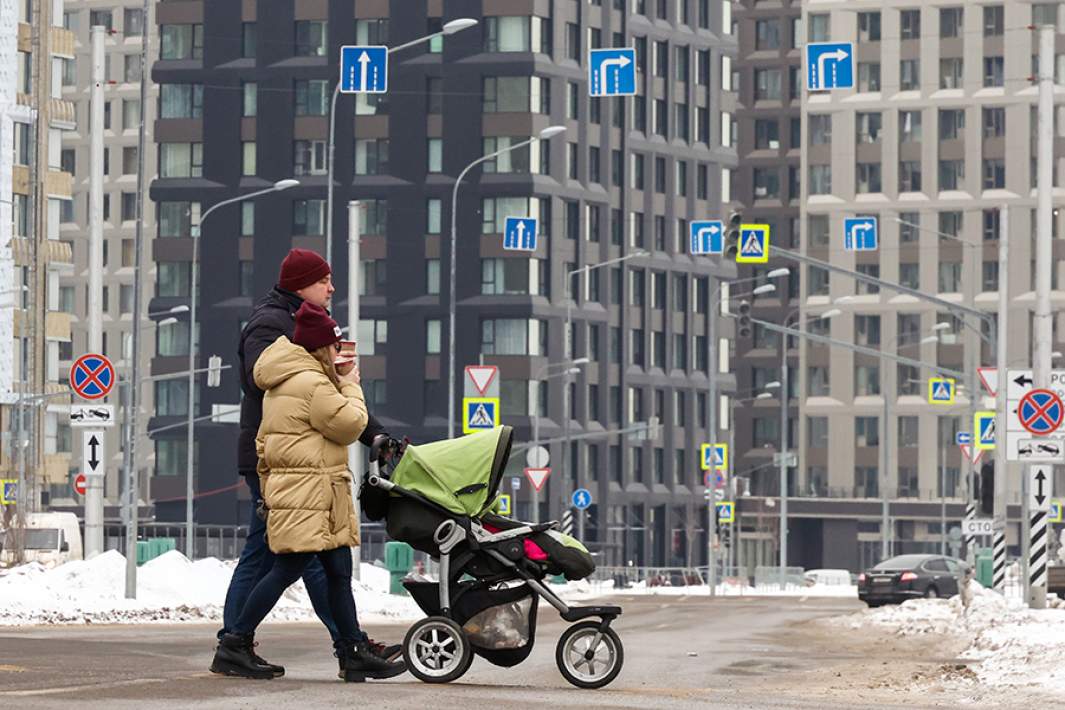 Семья с ребенком идет мимо строящихся домов жилого комплекса