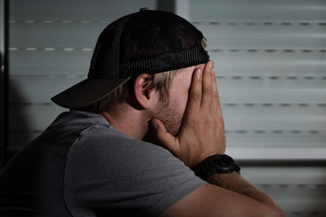 Мужчина закрывает лицо руками 