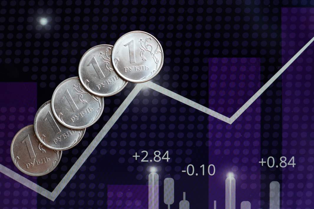 Монеты номиналом один рубль на фоне биржевого графика