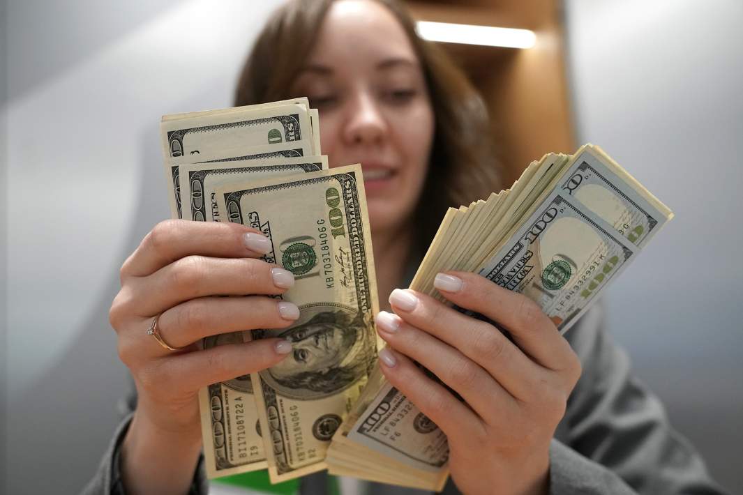 Сотрудник банка пересчитывает купюры различного номинала