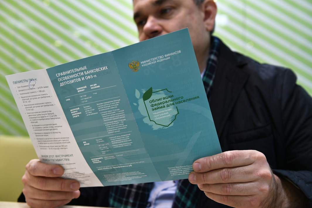 Мужчин изучает буклет о приобретении облигаций федерального займа