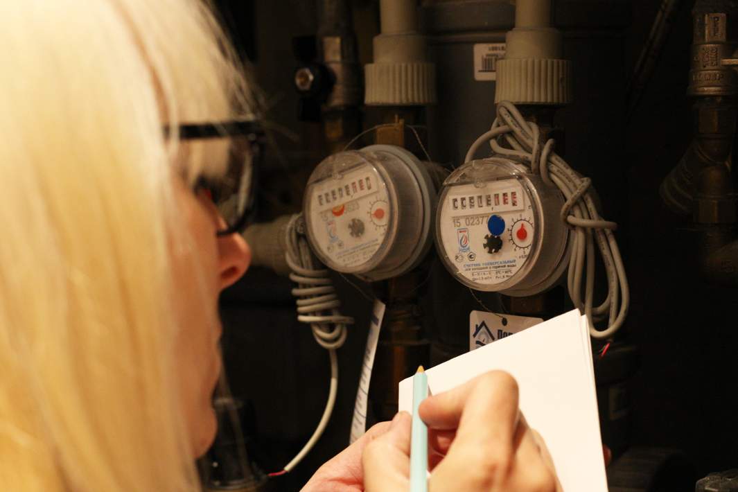 Женщина переписывает показания счетчиков 