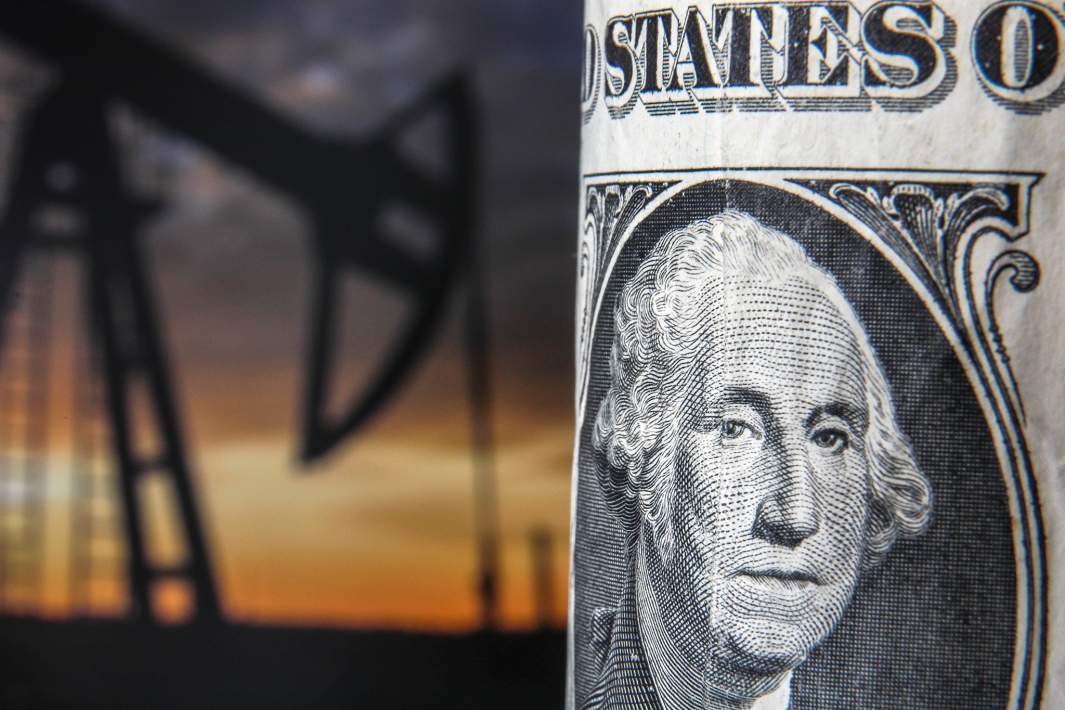  Банкнота номиналом один доллар США на фоне нефтяных вышек