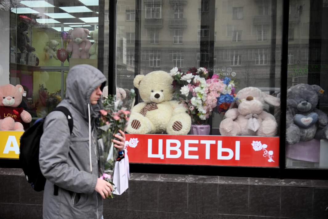 Молодой человек проходит мимо витрины магазина с сувенирной продукцией