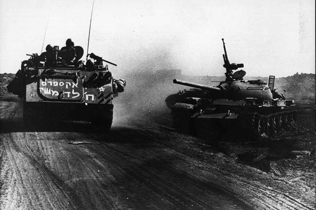 Израильский БТР проезжает мимо уничтоженного египетского танка во время Войны Судного дня
