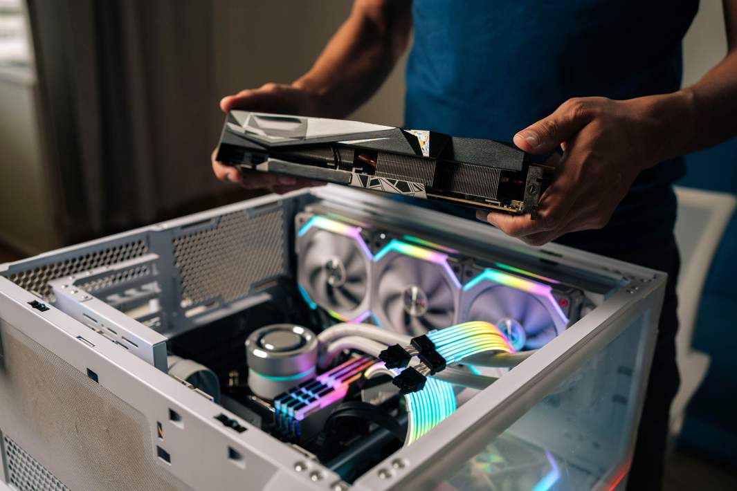 Мужчина устанавливает видеокарту в компьютер
