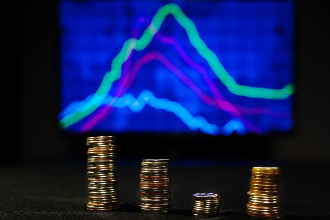 Стопки монет на фоне биржевого графика