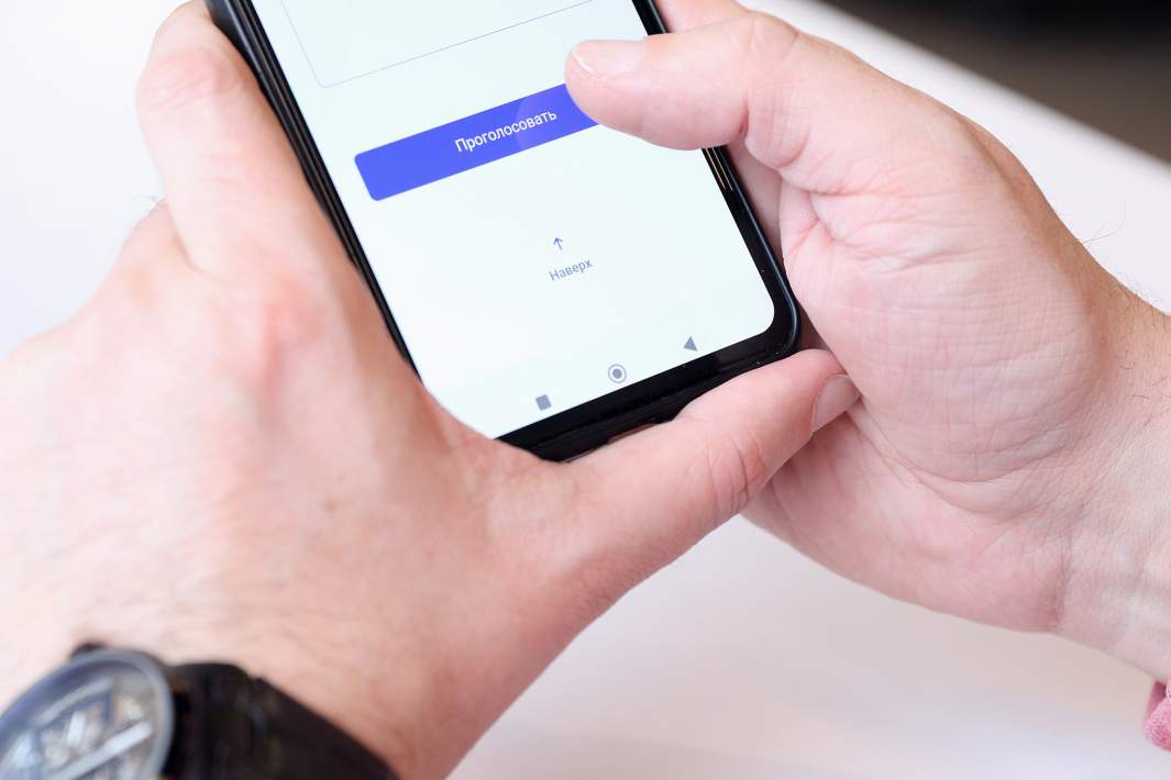 Молодой человек с телефоном в руках во время дистанционного электронного голосования