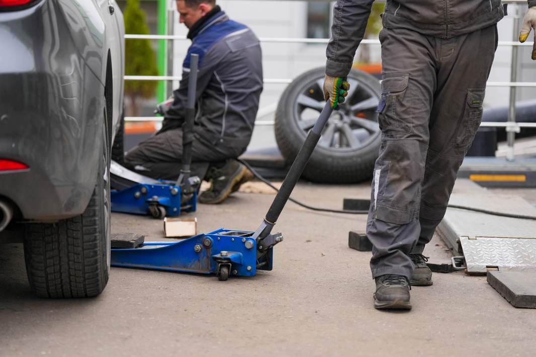Сотрудник шиномонтажа убирает домкрат 