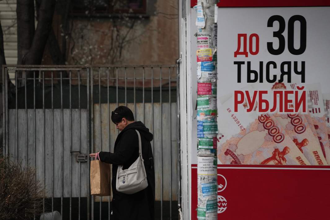 Люди идут мимо офиса микрофинансовой организации