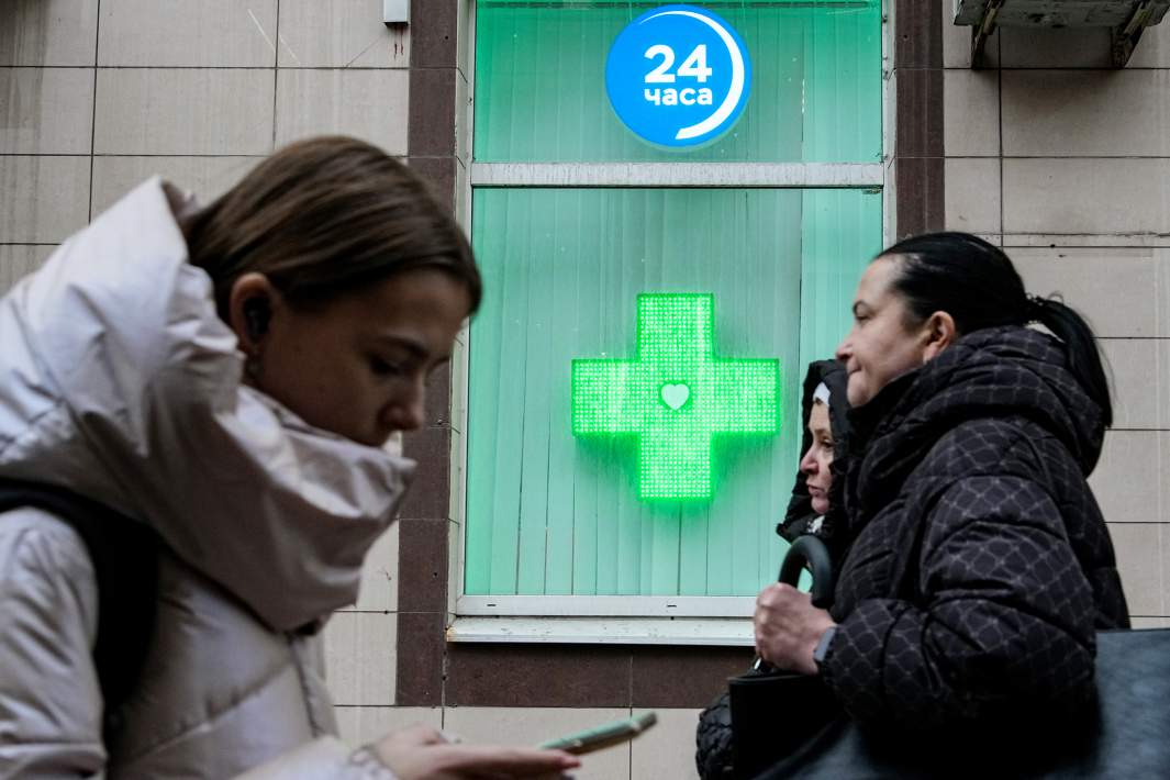 Люди идут мимо аптеки