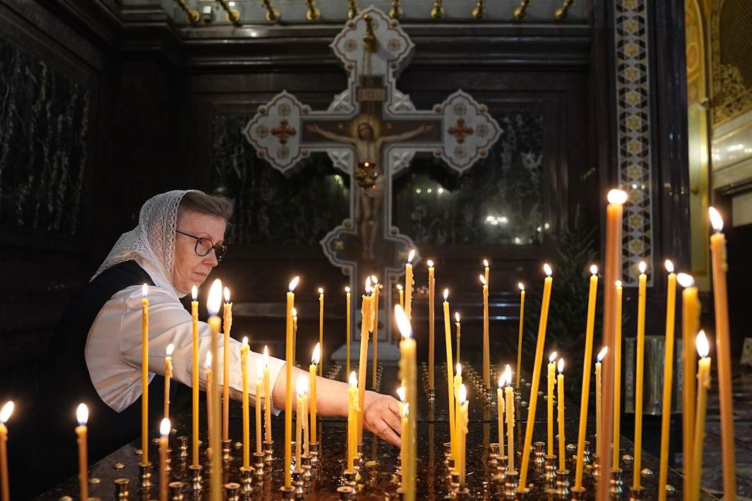 Женщина ставит свечи в храме 