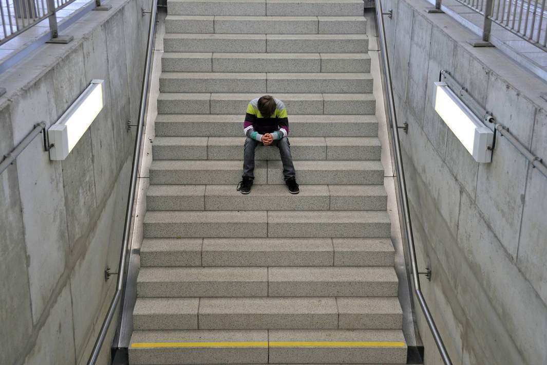 Подросток сидит на лестнице 
