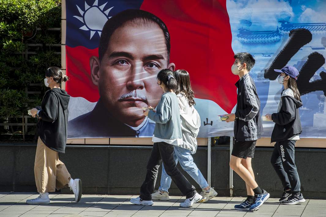 Прохожие проходят мимо изображения Сунь Ятсена — лидера и основателя Гоминьдана