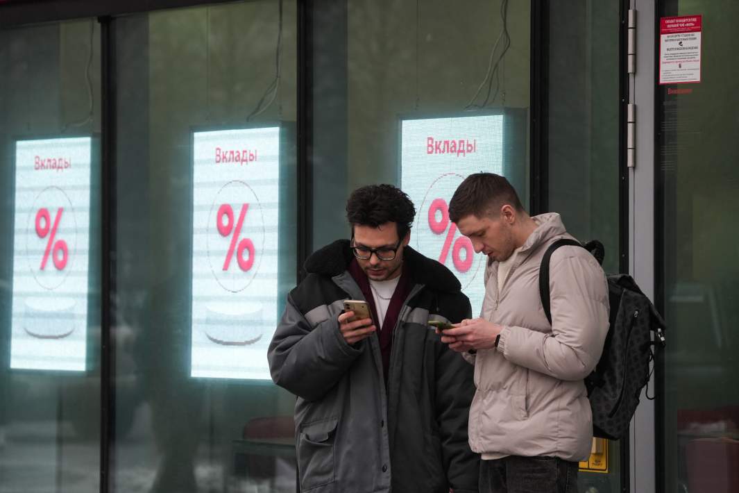 Мужчина стоят на фоне рекламы в витрине банка