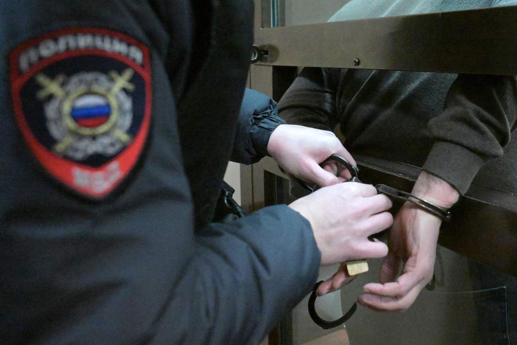 Сотрудник полиции надевает наручники на подозреваемого